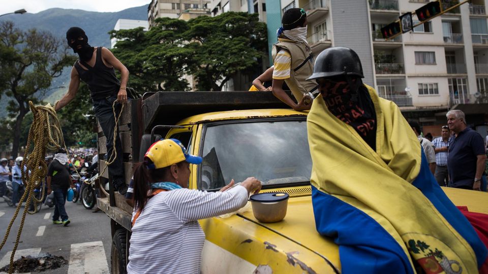 Volksaufstand in Venezuela: Eine Regimegegnerin versorgt erschöpfte Frontkämpfer mit Essen Eine Regimegegnerin versorgt erschöpfte Frontkämpfer mit Essen
