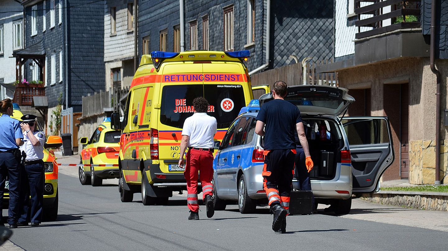 Ein Rettungswagen und ein Polizeiauto stehen vor einem mit Schiefer verkleideten Haus, in dem sich ein Familiendrama abspielte