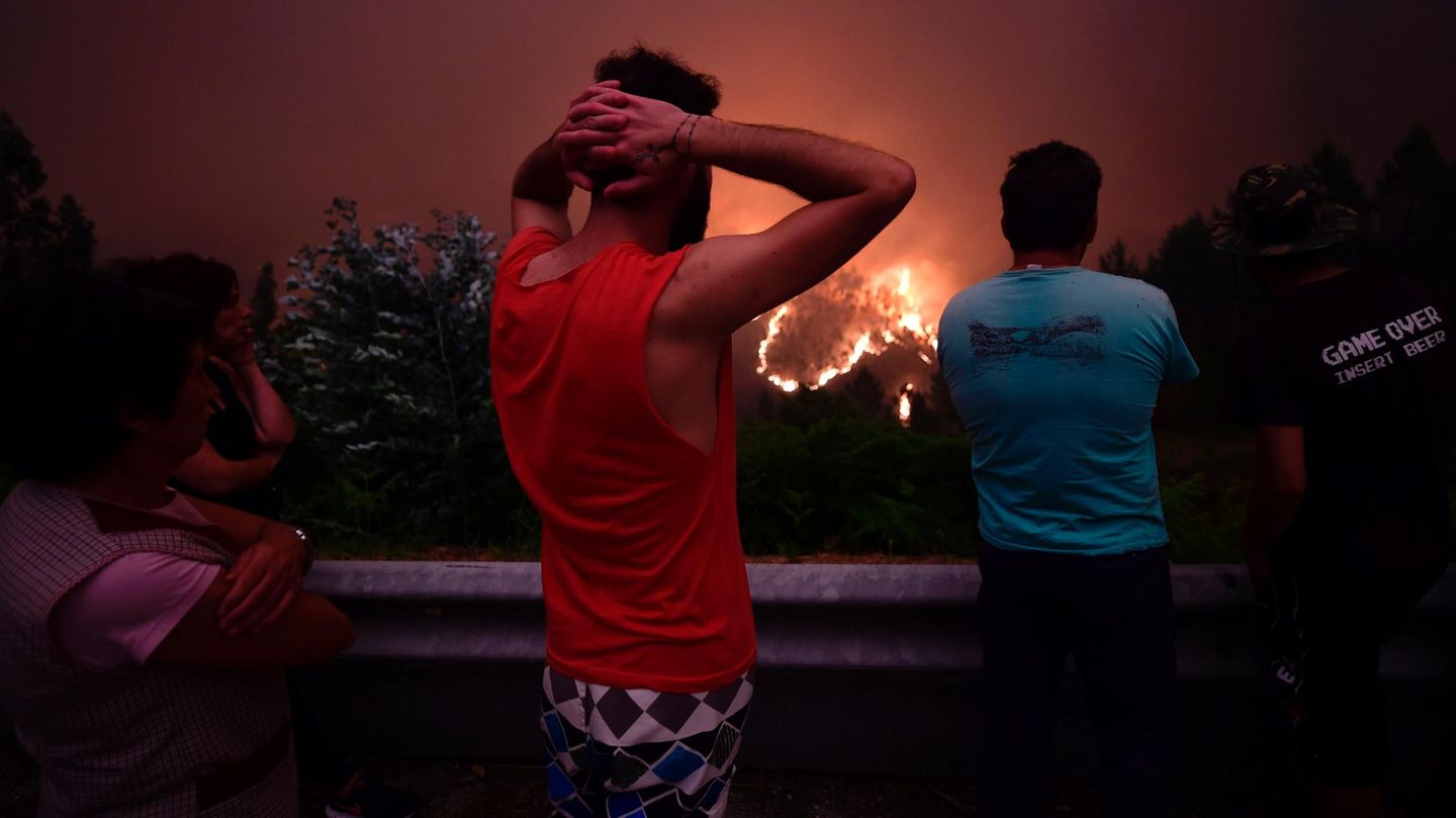 Bewohner blicken auf einen Waldbrand in der Nähe des Dorfes Mega Fundeira in Portugal
