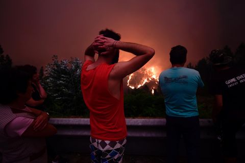 Bewohner blicken auf einen Waldbrand in der Nähe des Dorfes Mega Fundeira in Portugal