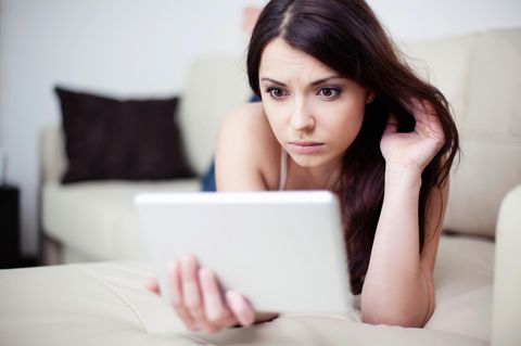 Eine Frau start erschrocken auf ihr Tablet. Singles bei Parship haben oft Ärger mit der Kündigung