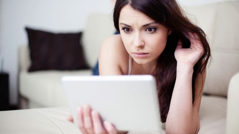 Eine Frau start erschrocken auf ihr Tablet. Singles bei Parship haben oft Ärger mit der Kündigung