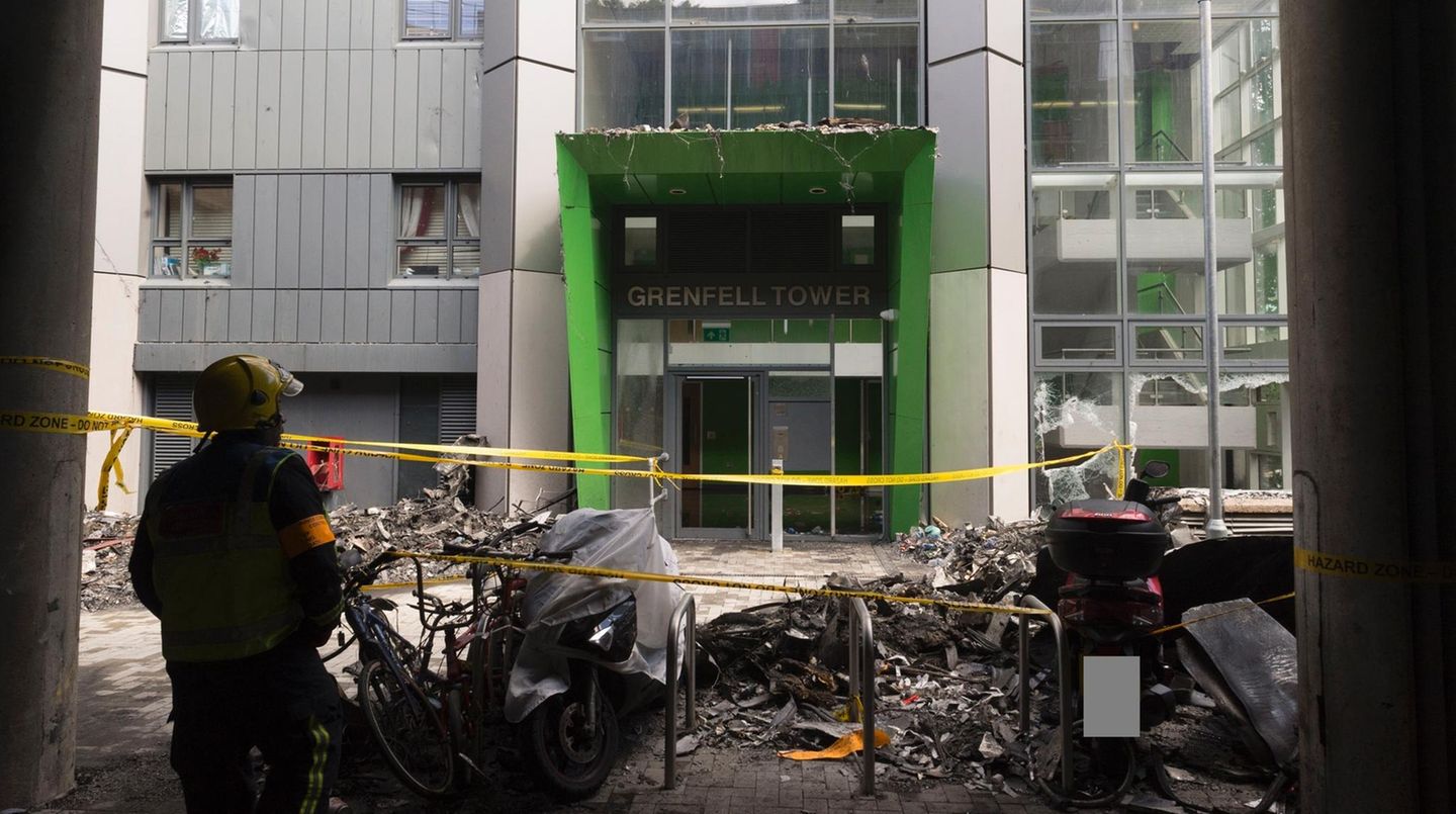 Ein Feuerwehrmann steht vor dem Eingang des 24-stöckigen Grennfell Towers