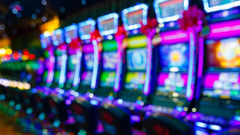 Eine Reihe von bunt beleuchteten Spielautomaten in einem Casino