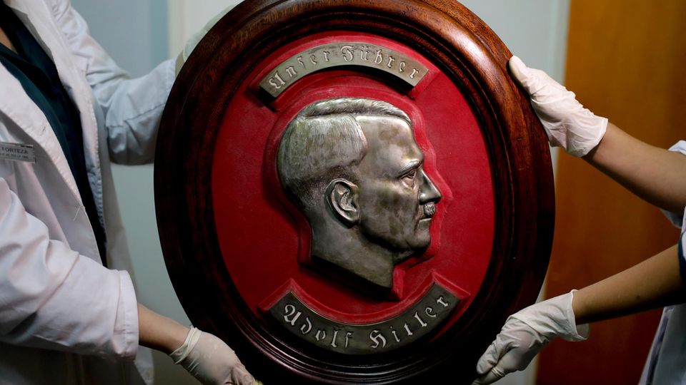 Mitglieder der Bundespolizei zeigen im Interpol-Hauptquartier in Buenos Aires ein gefundenes Relief von Adolf Hitler