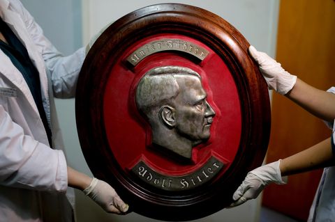 Mitglieder der Bundespolizei zeigen im Interpol-Hauptquartier in Buenos Aires ein gefundenes Relief von Adolf Hitler