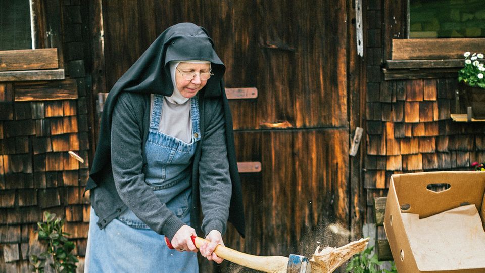 Schwester Dominica im Habit beim Holzhacken. Auch mit der Motorsäge kann sie umgehen