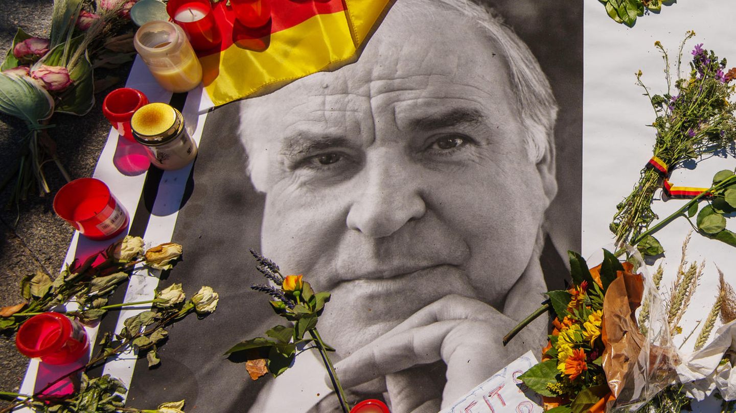 Kerzen und Blumen stehen auf einem Bild des verstorbenen Helmut Kohl