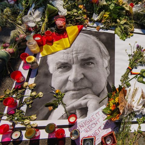 Kerzen und Blumen stehen auf einem Bild des verstorbenen Helmut Kohl