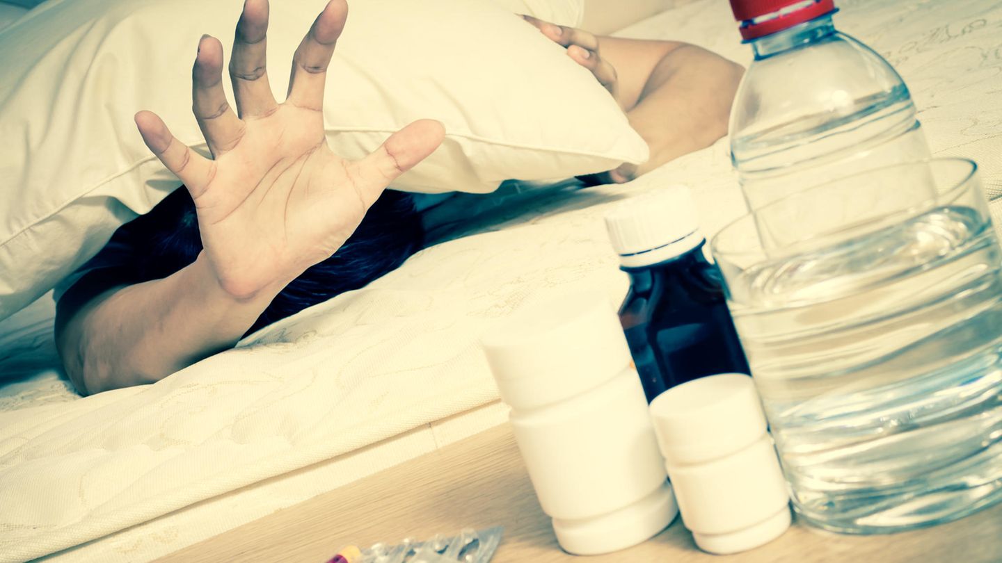 Ein Mann greift zu Kopfschmerztabletten