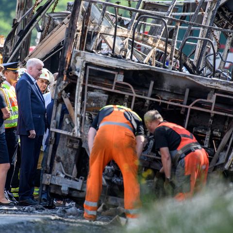 Busunglück in Bayern: Ministerpräsident Horst Seehofer steht zusammen mit Einsatzkräften an dem verunfallten Reisebus.