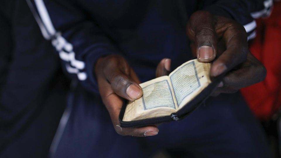 Während er auf die Ankunft in Italien wartet liest dieser Mann im Koran