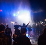 Ein Wasserwerfer der Polizei spritzt am Neuen Pferdemarkt im Stadtteil St. Pauli Wasser auf eine Menschenmenge. Hunderte Menschen hielten sich hier am Dienstagabend auf der Straße auf und behinderten den Verkehr, ehe die Polizei begann, den Neuen Pferdemarkt zu räumen. 