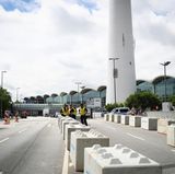 Polizeibeamte stehen an einer Durchlassstelle zum Sicherheitsbereich an der Rentzelstraße vor den Messehallen zwischen Betonpollern