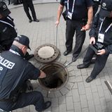 Mit Spiegeln, Sonden und Kameras untersuchen technische Einsatzkräfte der Bundespolizei einen Gully im Eingangsbereich für die Delegierten an den Messehallen