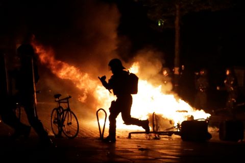 G20-Protest in Hamburg: Polizist als Schattenmann vor einem Feuer im Schanzenviertel