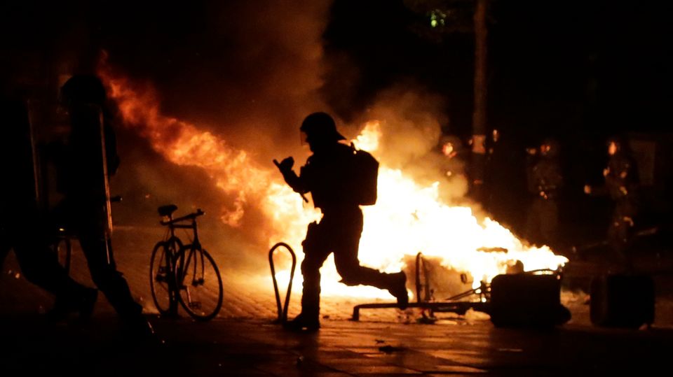 G20-Protest in Hamburg: Polizist als Schattenmann vor einem Feuer im Schanzenviertel