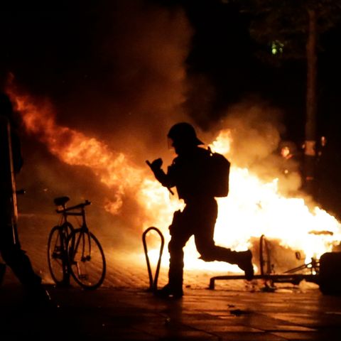 G20-Protest in Hamburg: Polizist als Schattenmann vor einem Feuer im Schanzenviertel