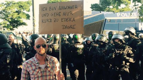 Mit viel Humor gegen den G20-Gipfel: "Ich bin so wütend, ich habe zum Einkaufen gehen ein Schild gemacht", schreibt der Comedian Andre Kramer auf Facebook und lässt sich vor einer Polizeikolonne fotografieren.