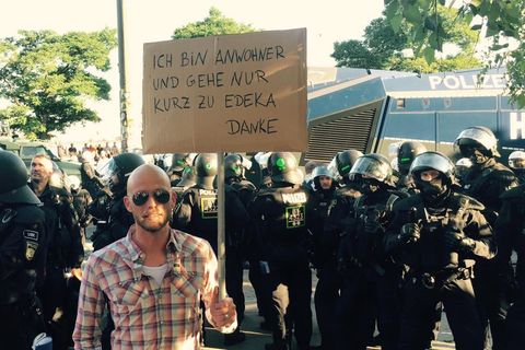 Mit viel Humor gegen den G20-Gipfel: "Ich bin so wütend, ich habe zum Einkaufen gehen ein Schild gemacht", schreibt der Comedian Andre Kramer auf Facebook und lässt sich vor einer Polizeikolonne fotografieren.