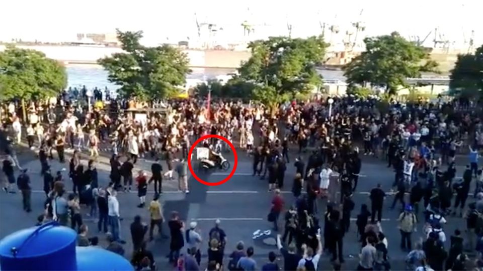 Pizzabote G20-Gipfel Ein Pizzabote fährt seine Lieferung auf dem Mofa mitten durch die Demonstranten