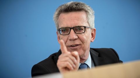 Vor blauem Hintergrund gestikuliert Bundesinnenminister Thomas de Maizière mit gestrecktem rechten Zeigefinger