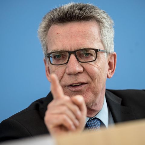 Vor blauem Hintergrund gestikuliert Bundesinnenminister Thomas de Maizière mit gestrecktem rechten Zeigefinger