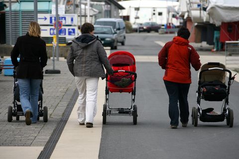 Streit um einen Kinderwagenstellplatz eskaliert. Drei Mütter laufen mit ihren Kinderwagen eine Straße entlang. (Symbolbild)