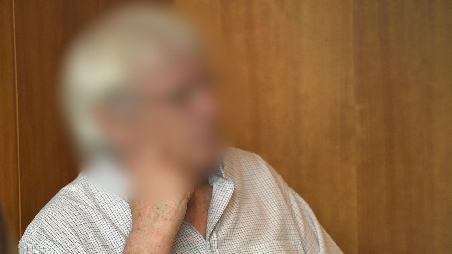 Ein weißhaariger Mann mit Brille sitzt vor einer hellbraunen Holzwand in einem Saal des Landgerichts Bonn