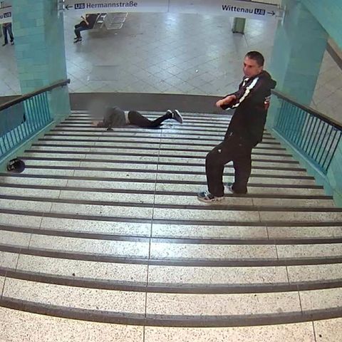 Fahndungsfoto der Polizei Berlin: Der Tatverdächtige steht am oberen Ende der U-Bahn-Treppe, während ein Mann herunter fällt.