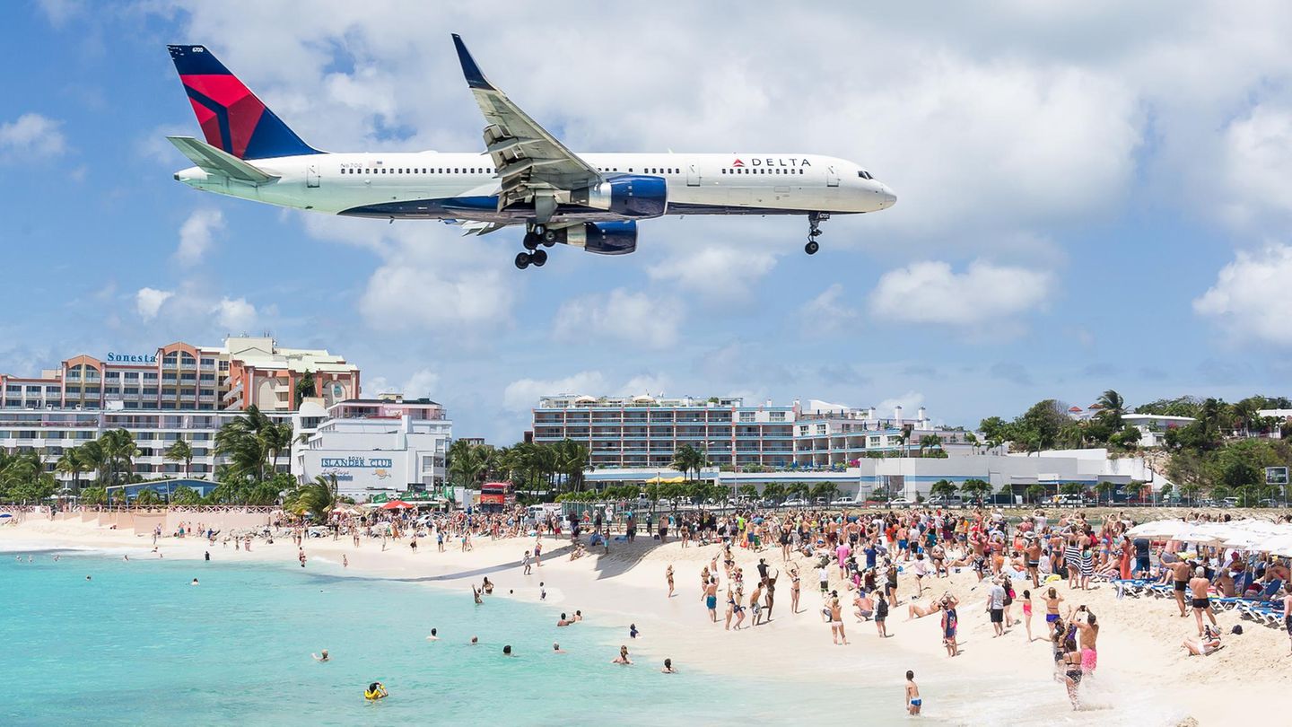 Auf Sint Maarten fliegt ein Flugzeug dicht über die Badegäste hinweg auf die Landebahn des Fluhafens zu