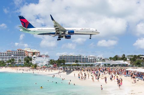 Auf Sint Maarten fliegt ein Flugzeug dicht über die Badegäste hinweg auf die Landebahn des Fluhafens zu