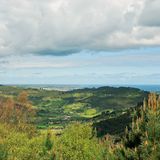 Nach dem Alto de la Cruz: Blick über das Tal von Peón bis nach Gijón und zum Meer.