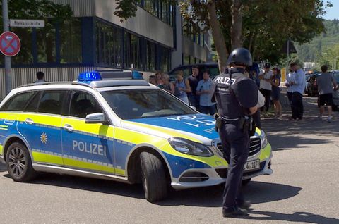 Ein Polizist steht mit Waffe und Dienstwagen vor der Friedrich-Ebert-Schule in Esslingen, Baden-Württemberg