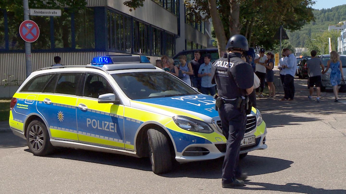 Ein Polizist steht mit Waffe und Dienstwagen vor der Friedrich-Ebert-Schule in Esslingen, Baden-Württemberg