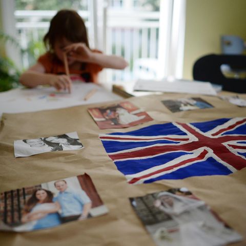 Ein kleines Mädchen sitzt am Tisch und malt. Vor ihr liegt die britische Flagge