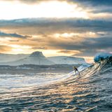 "Der Surfer Nic von Rupp surft eine winterliche Welle vor den schneebedeckten Bergen bei Bundoran, Irland."