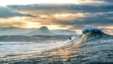 "Der Surfer Nic von Rupp surft eine winterliche Welle vor den schneebedeckten Bergen bei Bundoran, Irland."