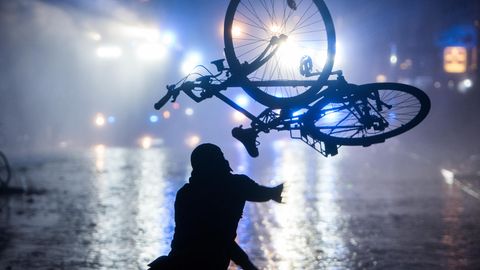 Ein Randalierer wirft in Hamburg im Schanzenviertel ein Fahrrad in Richtung von Wasserwerfern
