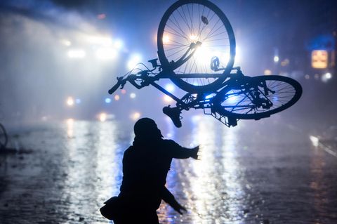 Ein Randalierer wirft in Hamburg im Schanzenviertel ein Fahrrad in Richtung von Wasserwerfern