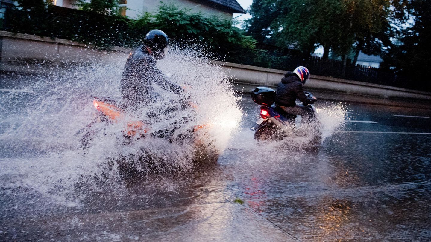 Zwei Motorradfahrer bahnen sich ihren Weg über eine überflutete Straße in der Region Hannover (Niedersachsen).