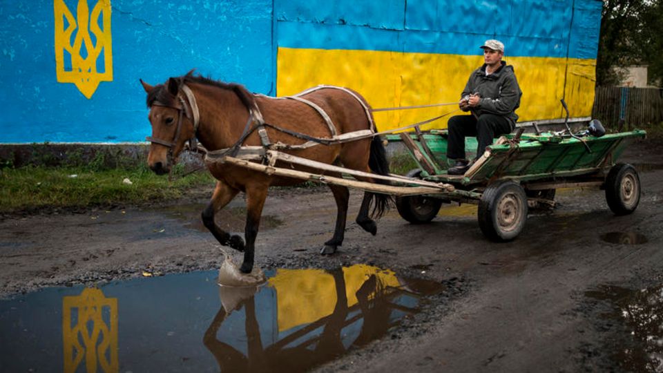 Ein Pferdekarren passiert die ukrainischen Nationalfarben am Marktplatz in Antonivka nahe der Grenze zu Weißrussland