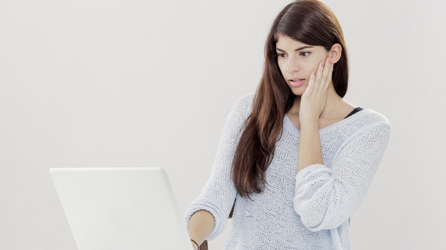 Eine Frau liest erschrocken eine E-Mail