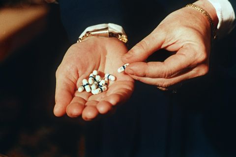 Zu sehen ist eine offene Handfläche, in der einige Tabletten liegen. Hier das HIV-Medeikament Retrovir.