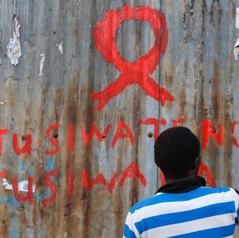 Ein Mann in Nairobi malt eine Aids-Schleife an eine Wand im Kibera-Schlam