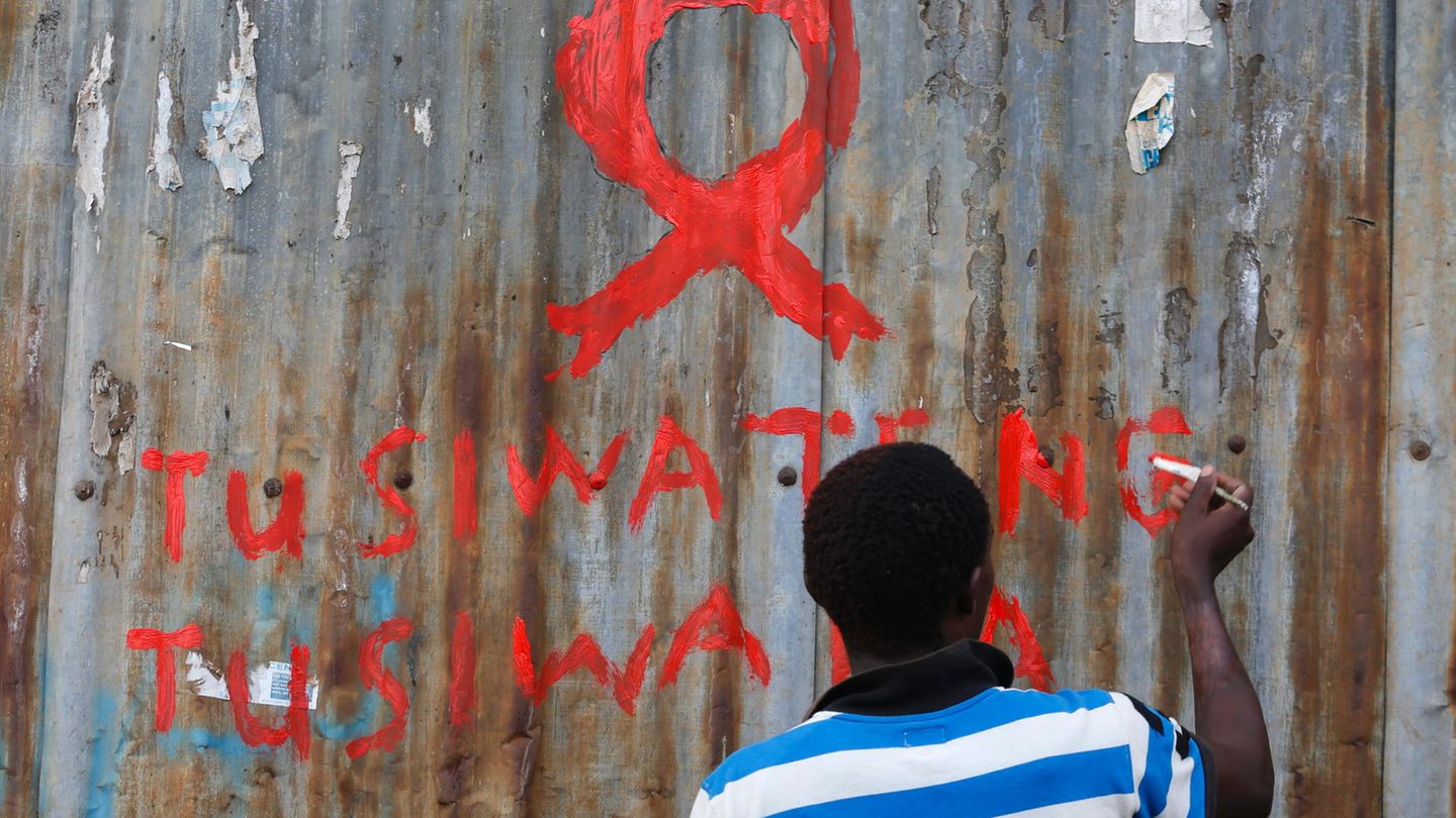 Ein Mann in Nairobi malt eine Aids-Schleife an eine Wand im Kibera-Schlam