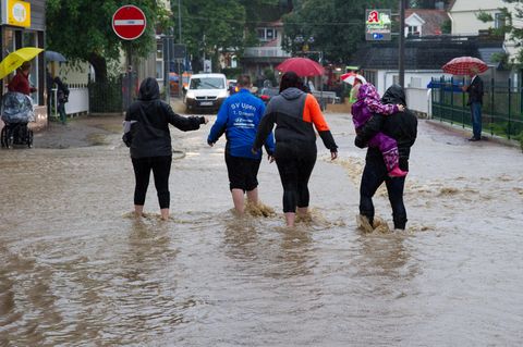 Sommer 2017: Eine Gruppe Menschen watet durch nach Dauerregen überflutete Straßen in Bad Harzburg