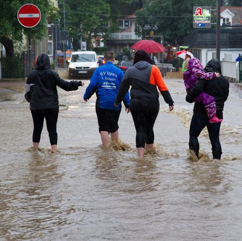 Sommer 2017: Eine Gruppe Menschen watet durch nach Dauerregen überflutete Straßen in Bad Harzburg