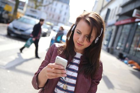 Eine junge Frau läuft über die Straße, während sie auf ihrem Handy schreibt