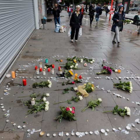 Blumen und Kerzen liegen am Samstag in ein Peace-Zeichen auf dem Bürgersteig vor dem Hamburger Supermarkt, in dem am Freitag ein Mann einen Menschen mit einem Messer getötet und sechs weitere verletzt hat. 